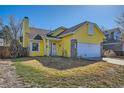 Quaint yellow home features a well-maintained lawn and attached garage on a clear day at 4386 Sable St, Denver, CO 80239