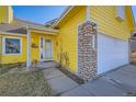 Inviting yellow home exterior with stone accents, an attached garage, and a tidy front lawn at 4386 Sable St, Denver, CO 80239