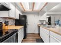 Efficient kitchen with white cabinetry, warm wood countertops, and modern black appliances, offering a practical cooking space at 16001 E Alaska Pl # 12, Aurora, CO 80017