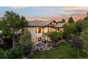 Back exterior with a large patio, manicured lawn, mature trees, and inviting outdoor spaces at 422 Suffolk Ln, Castle Rock, CO 80108