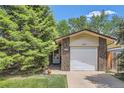 The garage of this home features brick and siding and a well-manicured lawn with a tree at 2208 Emery St, Longmont, CO 80501