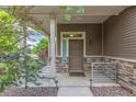 Inviting front porch with stone accents, modern lighting, and a stylish entry door at 18112 E 104Th Way, Commerce City, CO 80022