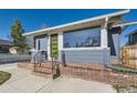 Home's entrance features a modern lime green door, complemented by a brick foundation and black iron railings at 4441 N Meade St, Denver, CO 80211