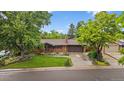 Charming brick home with a well-manicured lawn, mature trees and a two-car garage at 7077 Dudley Dr, Arvada, CO 80004