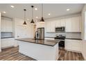 Modern kitchen featuring stainless steel appliances, dark countertops, and an island with stylish pendant lighting at 2491 W 69Th Pl, Denver, CO 80221
