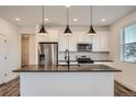Modern kitchen featuring stainless steel appliances, dark countertops, and an island with stylish pendant lighting at 2491 W 69Th Pl, Denver, CO 80221