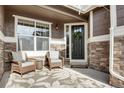 Cozy front porch features stylish seating, decorative wreath and stone accents at 25669 E Fair Dr, Aurora, CO 80016