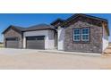 Home exterior showing attached three-car garage with stone and vertical siding at 56159 E Tomahawk Ave, Strasburg, CO 80136