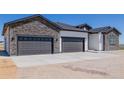 New home exterior showing attached three-car garage with stone and white siding at 56159 E Tomahawk Ave, Strasburg, CO 80136