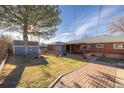 A fenced backyard features a patio, shed, mature tree, and lush lawn at 971 Elm Pl, Thornton, CO 80229