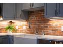 Close up of a kitchen sink featuring gray cabinets, white countertop and stainless faucet over an exposed brick backsplash at 1801 Wynkoop St # 518, Denver, CO 80202