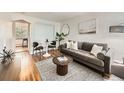 Inviting living room with a plush gray sofa, stylish decor, a round table, and hardwood floors at 4418 W 11Th Ave, Denver, CO 80204