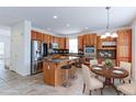 Well-lit kitchen features wood cabinets, granite countertops, stainless steel appliances, and a kitchen island with bar stool seating at 2631 E 136Th Pl, Thornton, CO 80602