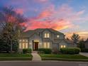 Charming two-story home with a beautiful lawn, shrubs, and a well-lit entryway at dusk at 5700 S Benton Cir, Littleton, CO 80123