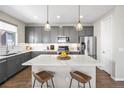 Modern kitchen features gray cabinets, stainless steel appliances, island with breakfast bar, and hardwood floors at 4265 E Iliff Ave # 1, Denver, CO 80222