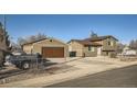 Home's exterior view featuring detached garage, driveway, chain-link fence and partial truck at 7611 Fernando Rd, Denver, CO 80221