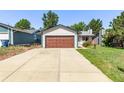 Charming single-story home featuring a large garage, well-maintained lawn, and colorful flower beds at 3735 S Lewiston St, Aurora, CO 80013