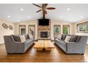 Inviting living room featuring a stone fireplace, wood floors, large windows, and cozy seating area at 10380 W Warren Ave, Lakewood, CO 80227