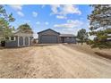 Residential home with a detached garage and gravel driveway is surrounded by mature trees at 6200 Bow Meadows Dr, Elizabeth, CO 80107