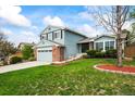 Two-story home with blue siding, a brick garage, green lawn, and decorative landscaping at 705 Prairie Ridge Rd, Highlands Ranch, CO 80126