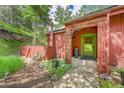 Close-up of the home's entrance featuring a green door, natural landscaping, and stone pathway at 23626 Genesee Village Rd, Golden, CO 80401