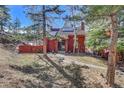 Attractive red home nestled among trees, featuring solar panels and a welcoming walkway at 23626 Genesee Village Rd, Golden, CO 80401
