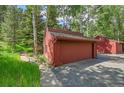 View of the red garage with two doors, located on the side of the home and nestled among the trees at 23626 Genesee Village Rd, Golden, CO 80401