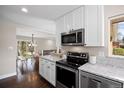 Open-concept kitchen featuring white cabinets, stainless appliances, and granite countertops at 991 E Applewood Ave, Centennial, CO 80121