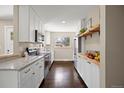 Galley kitchen with white cabinets, stainless steel appliances, butcher block and granite countertops at 991 E Applewood Ave, Centennial, CO 80121