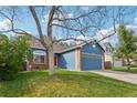 Charming blue home featuring a well-manicured lawn, brick accents, and a two-car garage at 7061 Palisade Dr, Highlands Ranch, CO 80130