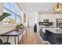 Bright, open kitchen featuring modern appliances, white cabinetry, an island and wood floors at 700 Lillibrook Pl, Erie, CO 80026