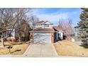 Charming two-story home boasts a gray exterior, brick accents, and a well-manicured front yard and large driveway at 16117 Ledge Rock Dr, Parker, CO 80134