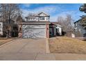 Charming two-story home boasts a gray exterior, brick accents, and a well-manicured front yard and large driveway at 16117 Ledge Rock Dr, Parker, CO 80134