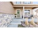 Inviting front porch with stylish seating, stone accents, and a welcoming wreath on the door at 3488 Purcell St, Brighton, CO 80601