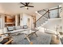 Bright living area with wood floors, a staircase, and an open layout leading to the kitchen at 1710 S Poplar St, Denver, CO 80224