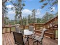 Inviting outdoor deck featuring a glass table with seating for four and scenic views of the surrounding greenery at 4295 Picutis Rd, Indian Hills, CO 80454