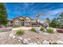 Beautiful home with decorative statue, well-manicured lawn, and rock landscaping at 1127 Buttermilk Rd, Larkspur, CO 80118