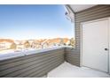 Balcony view of rooftops in snowy townhome community with a storage closet and gray siding at 912 S Yampa St # 206, Aurora, CO 80017