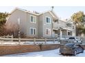 Corner view of a gray two story townhome exterior with patios, brick accents, and a gray fence in a snowy landscape at 912 S Yampa St # 206, Aurora, CO 80017