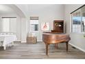 Bright living room with hardwood floors, neutral paint, large windows, and a vintage piano at 1788 Alpine Dr, Erie, CO 80516