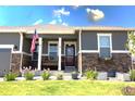 Inviting front porch with gray siding, stone accents, and a cozy porch swing at 599 Fall River Ct, Brighton, CO 80601