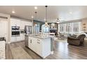 Open concept kitchen and living room featuring a fireplace, stainless appliances, and a breakfast bar at 599 Fall River Ct, Brighton, CO 80601