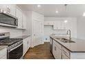 Bright kitchen boasts stainless steel appliances, white cabinets, and an island with a sink at 8374 E 132Nd Pl, Thornton, CO 80602