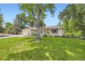 Lovely home exterior featuring a lush green lawn and a large shade tree at 5475 W Ottawa Ave, Littleton, CO 80128