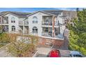 View of townhouses with balconies, stairs, brick accents, and a red car parked nearby at 1646 S Deframe St # B8, Lakewood, CO 80228