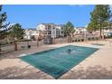 Community pool with a safety cover, surrounded by trees, a fence, and residential buildings at 1646 S Deframe St # B8, Lakewood, CO 80228