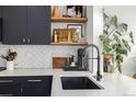 Modern kitchen featuring black cabinetry, white countertops, and a stylish sink with black faucet at 4925 W 10Th Ave # 111, Denver, CO 80204