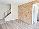 Spacious living room featuring wood-look flooring, a decorative wood plank wall, and a staircase with a black railing at 3225 S Garrison St # 19, Lakewood, CO 80227