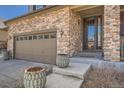 Close-up of home's stone facade, two-car garage, decorative planters, and front entrance at 77 N Jackson Gap Way, Aurora, CO 80018