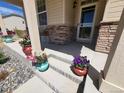 Inviting covered front porch featuring stone accents, flower decor, and shade from the sun at 1799 Jade Ave, Brighton, CO 80603